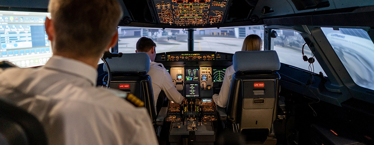 Blick in einen Cockpit-Simulator mit zwei Piloten und einem Ausbilder