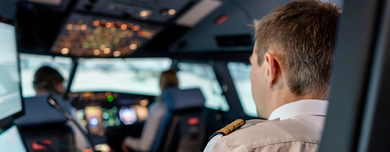 2 Piloten sitzen in einem Cockpit eines Flugzeugsimulators mit einem Trainer